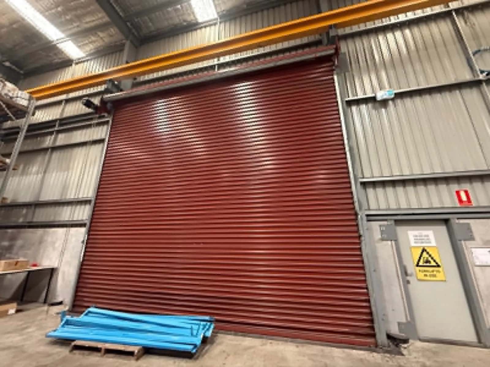 Technician servicing a heavy-duty industrial roller door at a Perth warehouse