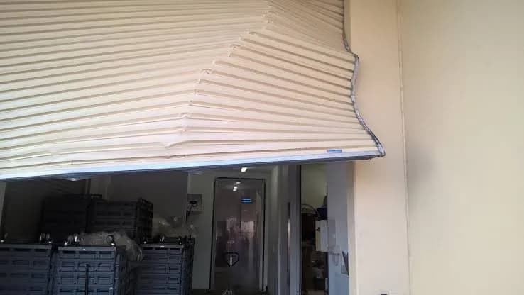 Commercial roller door with a crumpled curtain sagging over the entry to business premises