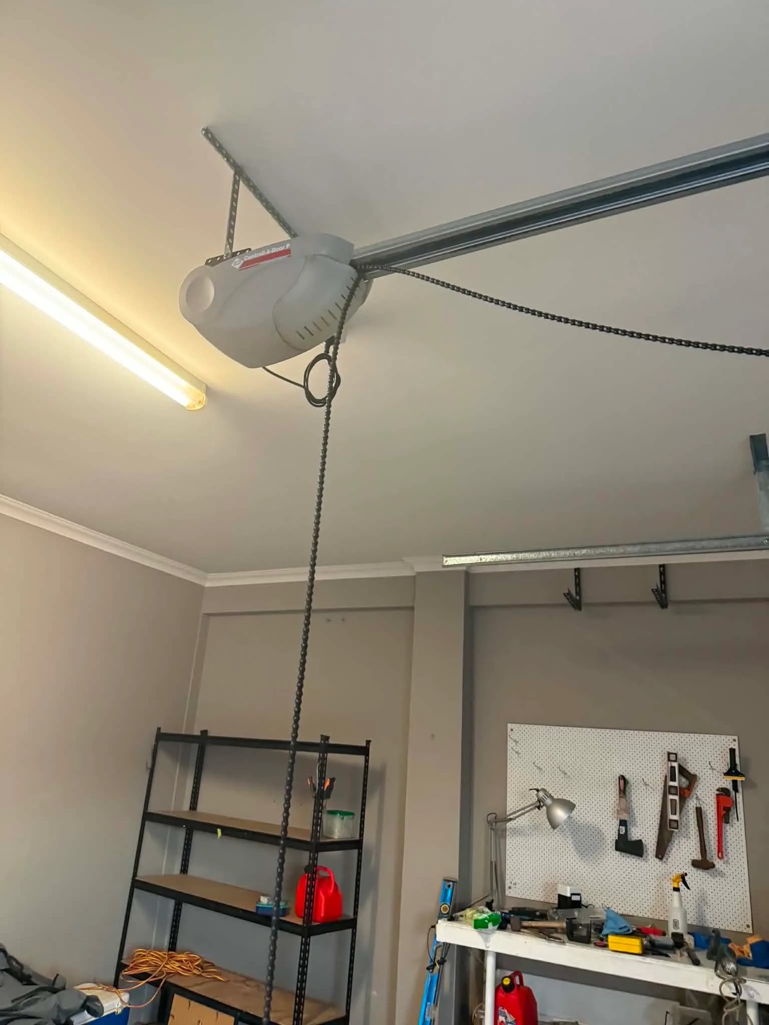 Chain-drive garage door opener being mounted to the ceiling rail during a motor installation