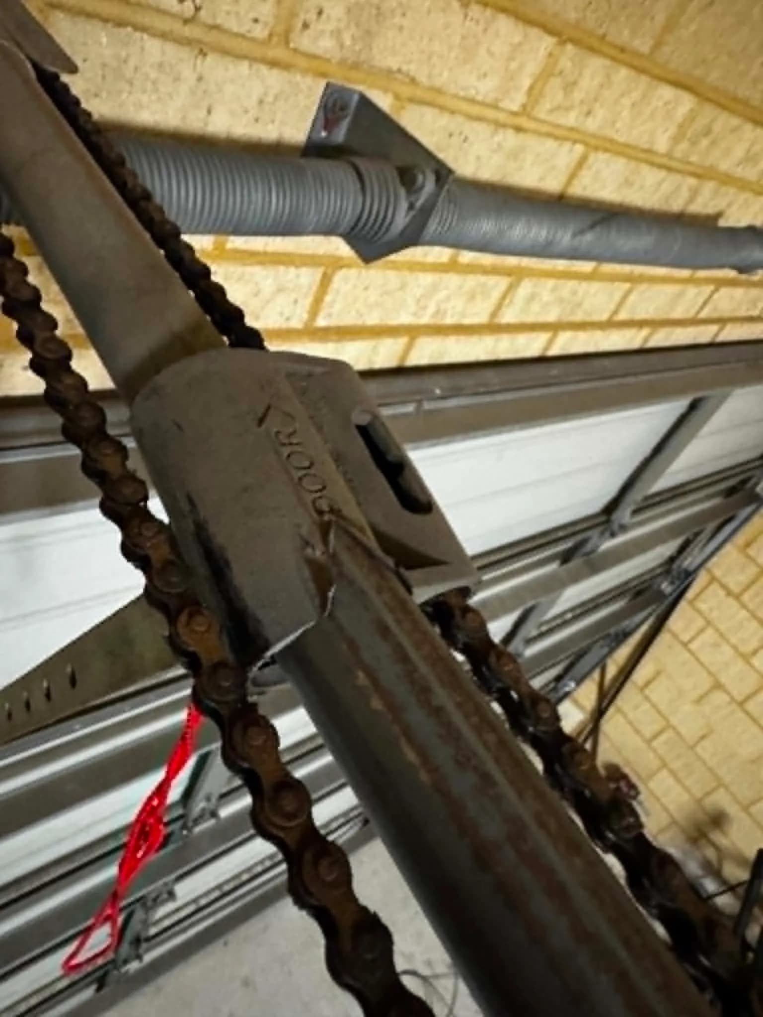 Torsion spring and chain-drive opener hardware during a spring repair on an older garage door
