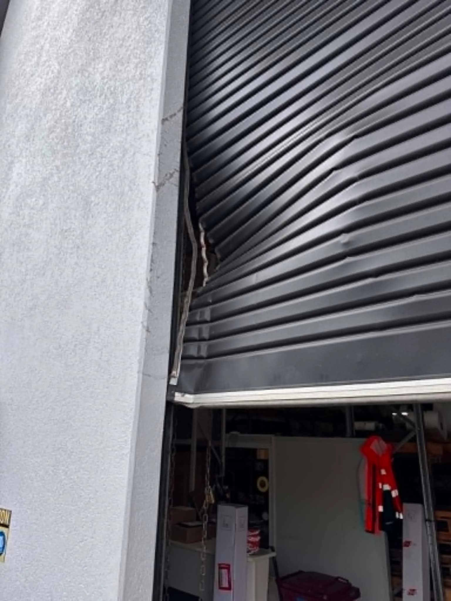 Charcoal roller door buckled out of its top guide beside a cracked wall in Cannington Charcoal roller door buckled out of its top guide beside a cracked wall in Cannington