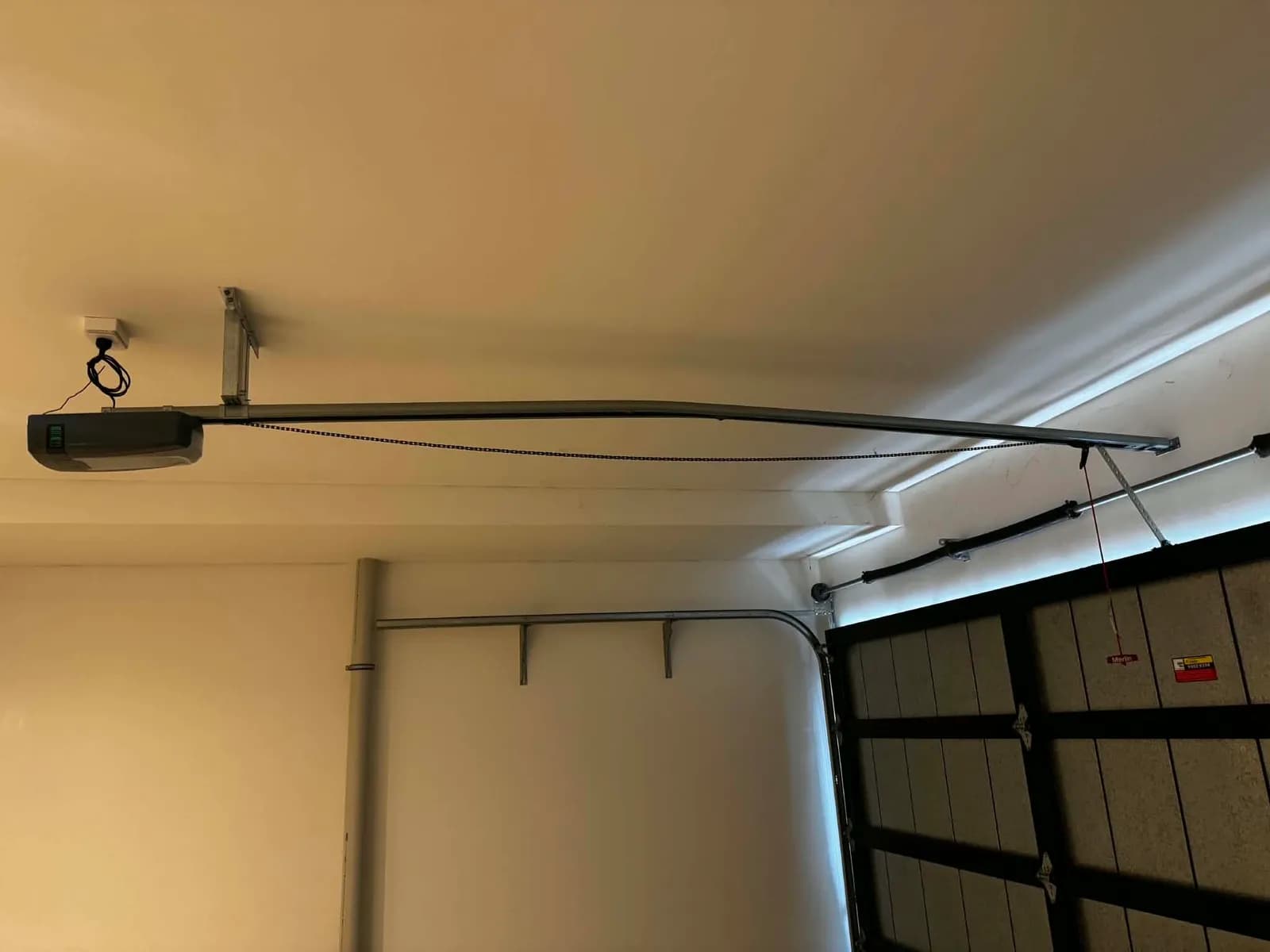 Belt-drive garage door opener mounted to the ceiling rail above a sectional door in Ellenbrook Belt-drive garage door opener mounted to the ceiling rail above a sectional door in Ellenbrook