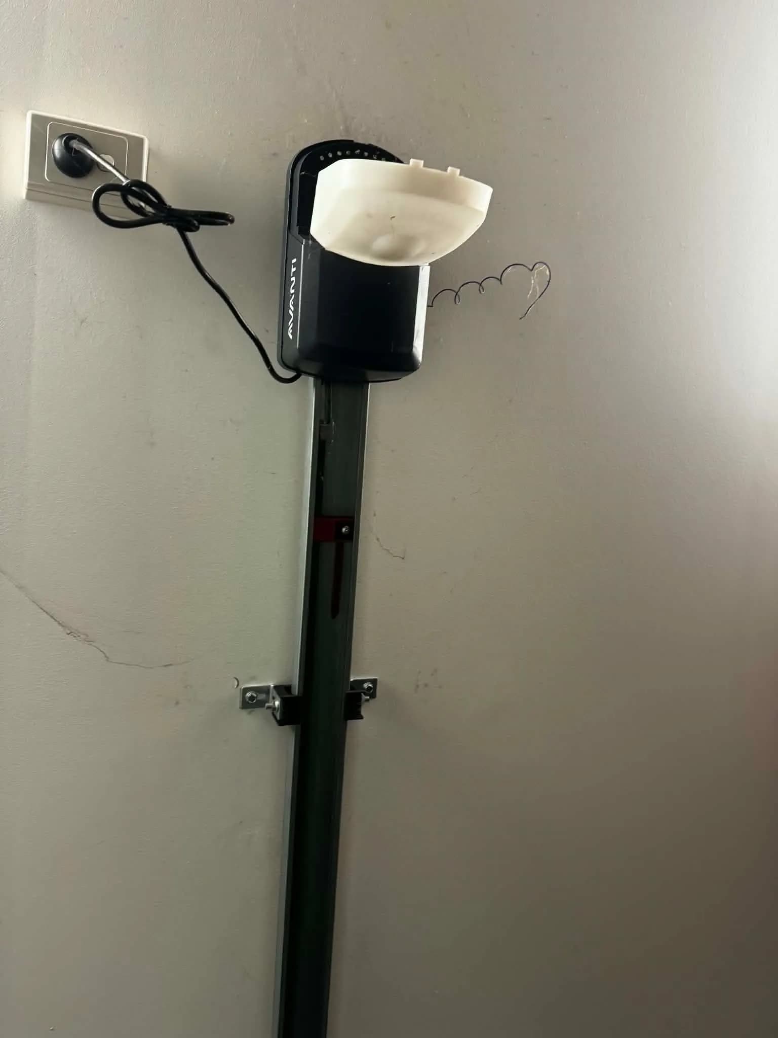 Failed Avanti garage door opener with its light cover hanging open above a sectional door in Butler, Perth before replacement Failed Avanti garage door opener with its light cover hanging open above a sectional door in Butler, Perth before replacement
