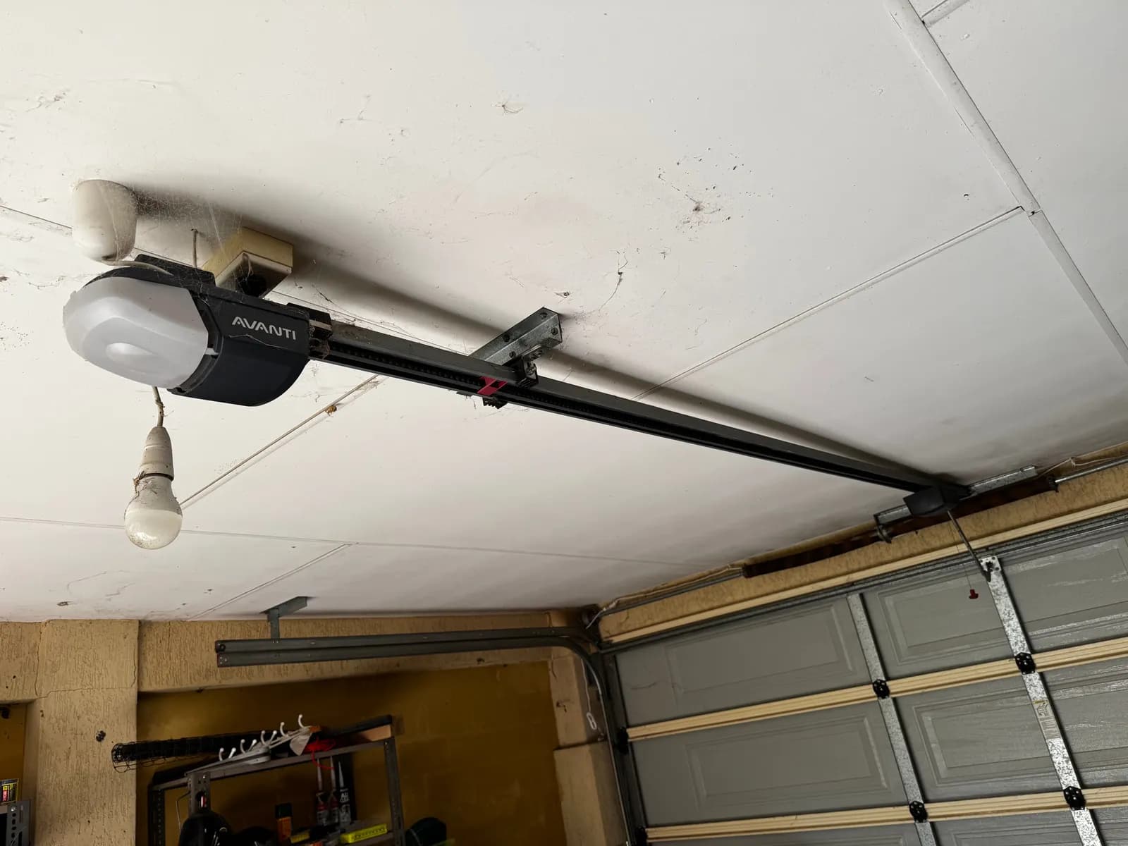 Old Avanti garage door opener on the ceiling rail above a grey sectional door in Caversham, Perth before replacement Old Avanti garage door opener on the ceiling rail above a grey sectional door in Caversham, Perth before replacement