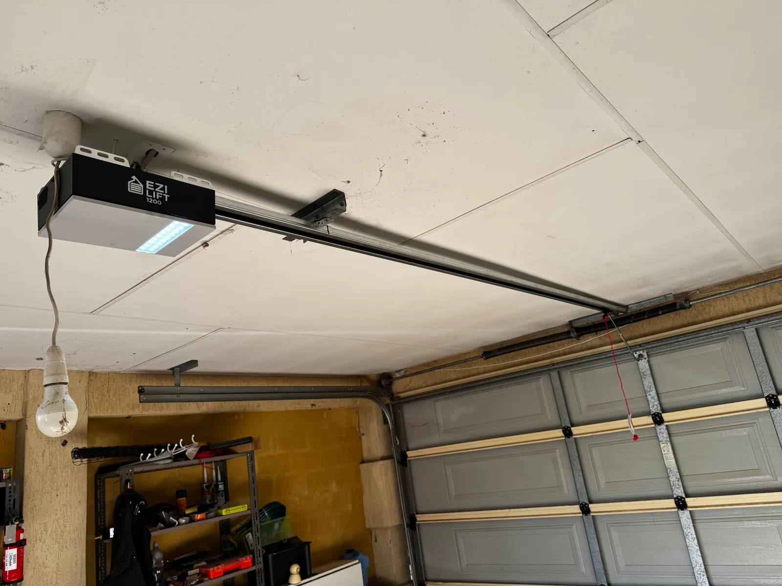 New Ezi-Lift 1200 garage door opener with LED light installed on the ceiling rail above a grey sectional door in Caversham, Perth New Ezi-Lift 1200 garage door opener with LED light installed on the ceiling rail above a grey sectional door in Caversham, Perth