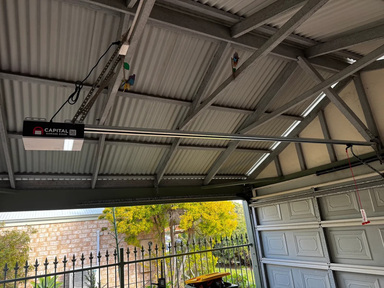 New Capital garage door motor with its LED light on, mounted above the door New Capital garage door motor with its LED light on, mounted above the door