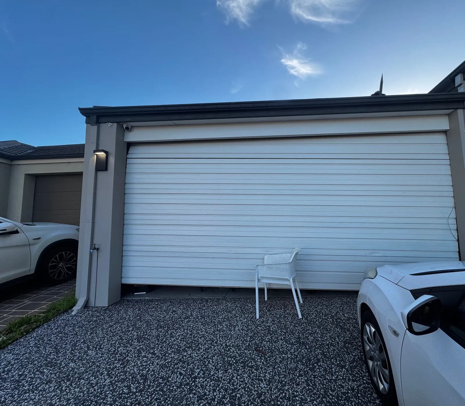White roller garage door in Byford, Perth sitting crooked with one side raised after a lift cable came off the drum White roller garage door in Byford, Perth sitting crooked with one side raised after a lift cable came off the drum