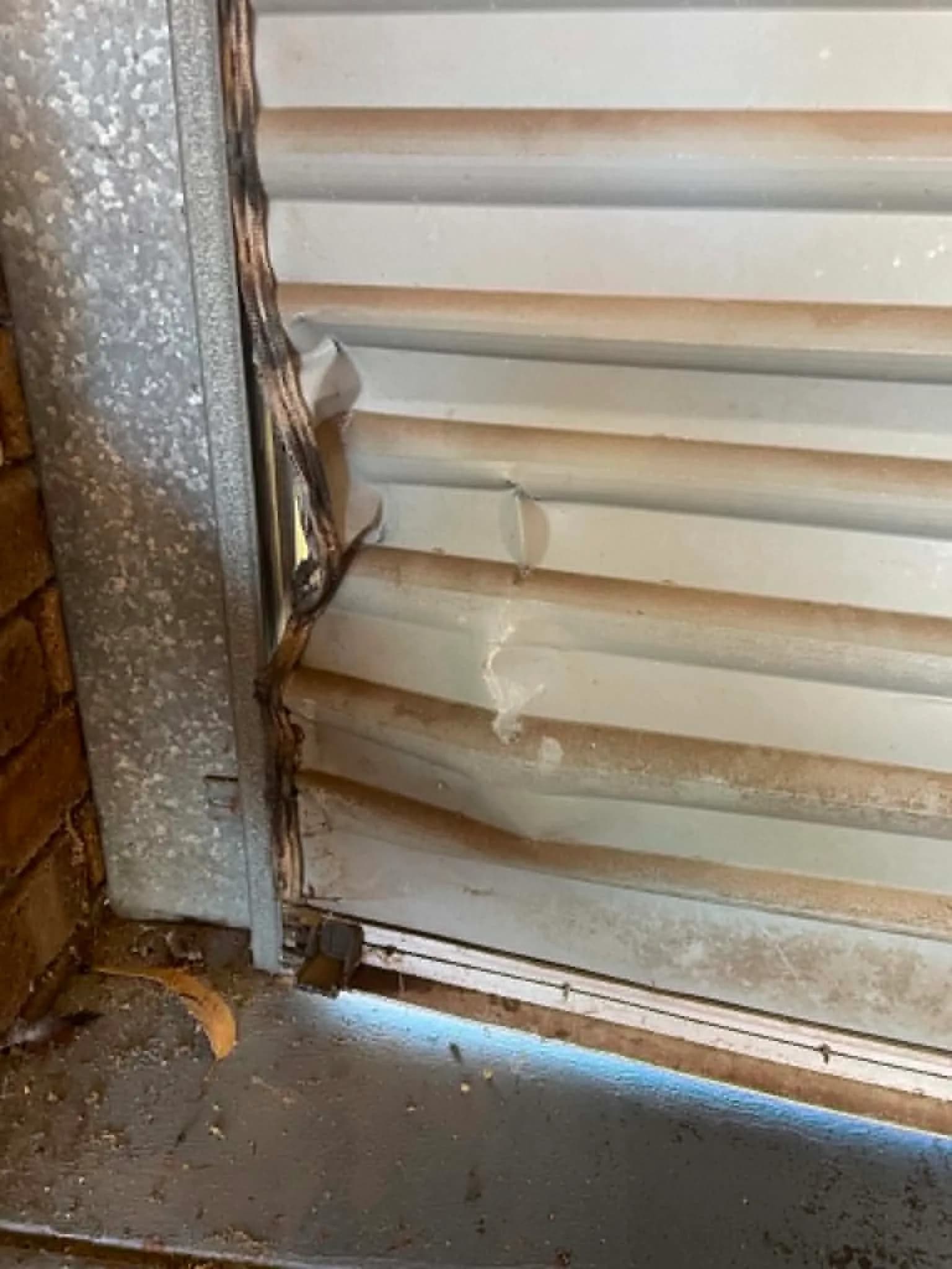 White roller door curtain pulled out of its side guide with bent slats in Gosnells White roller door curtain pulled out of its side guide with bent slats in Gosnells