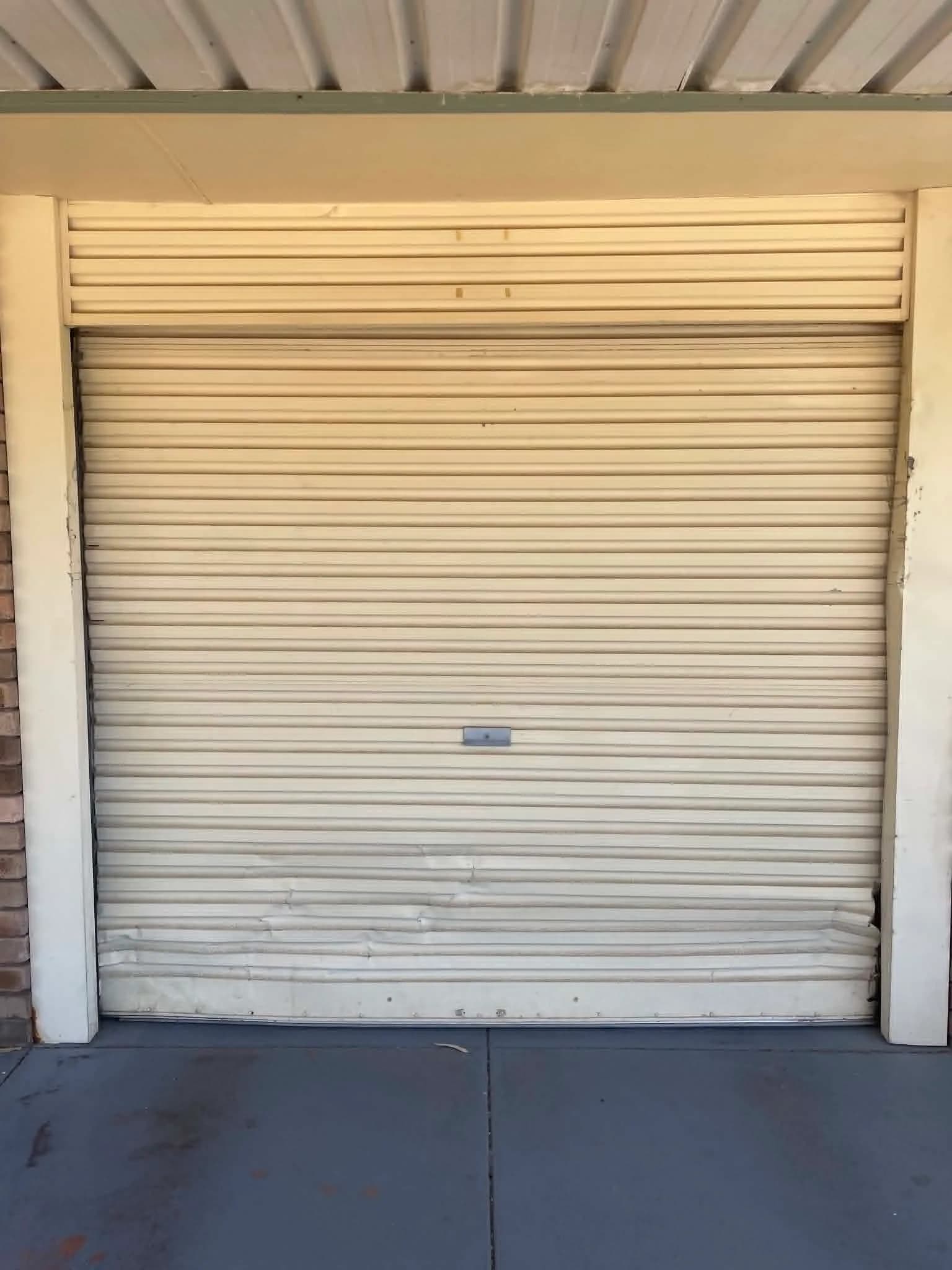 Old cream roller shutter door in Midland with dented, bowed bottom slats Old cream roller shutter door in Midland with dented, bowed bottom slats