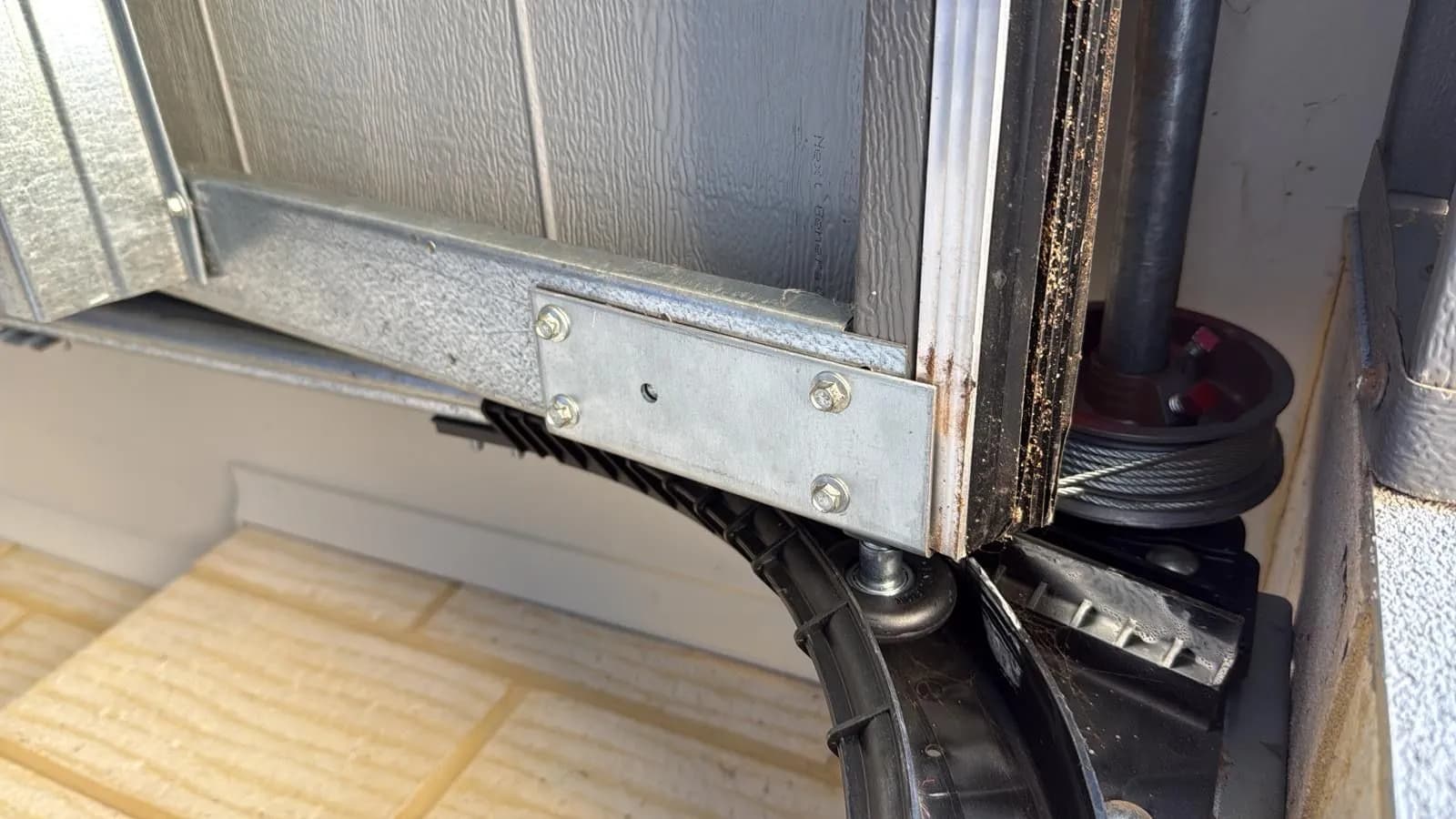 New galvanised bottom bracket, roller and lift cable fitted at the base of a sectional garage door in Spearwood, Perth New galvanised bottom bracket, roller and lift cable fitted at the base of a sectional garage door in Spearwood, Perth