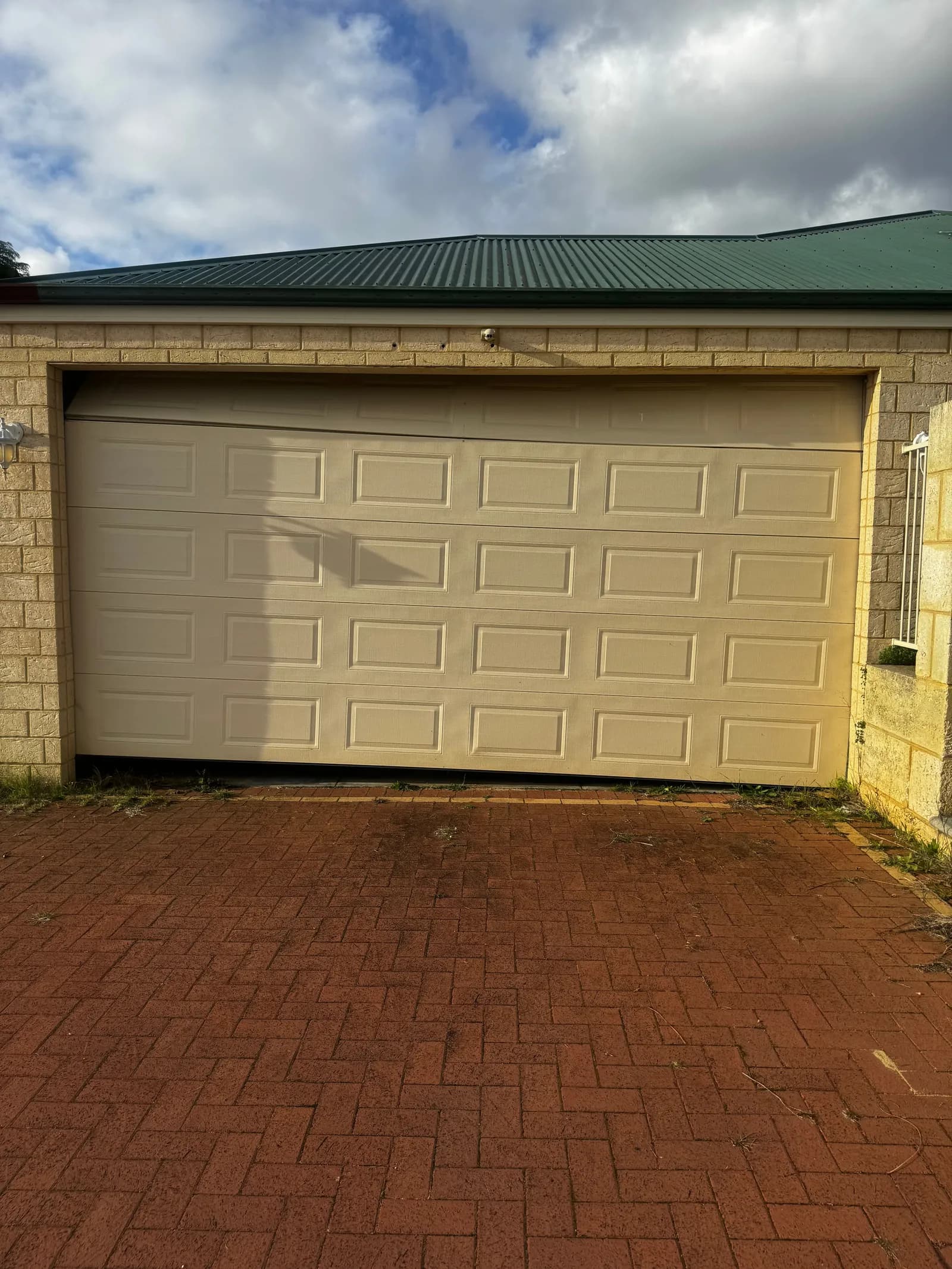 Cream double sectional garage door in Jane Brook, Perth sitting crooked in the opening after a lift cable snapped Cream double sectional garage door in Jane Brook, Perth sitting crooked in the opening after a lift cable snapped