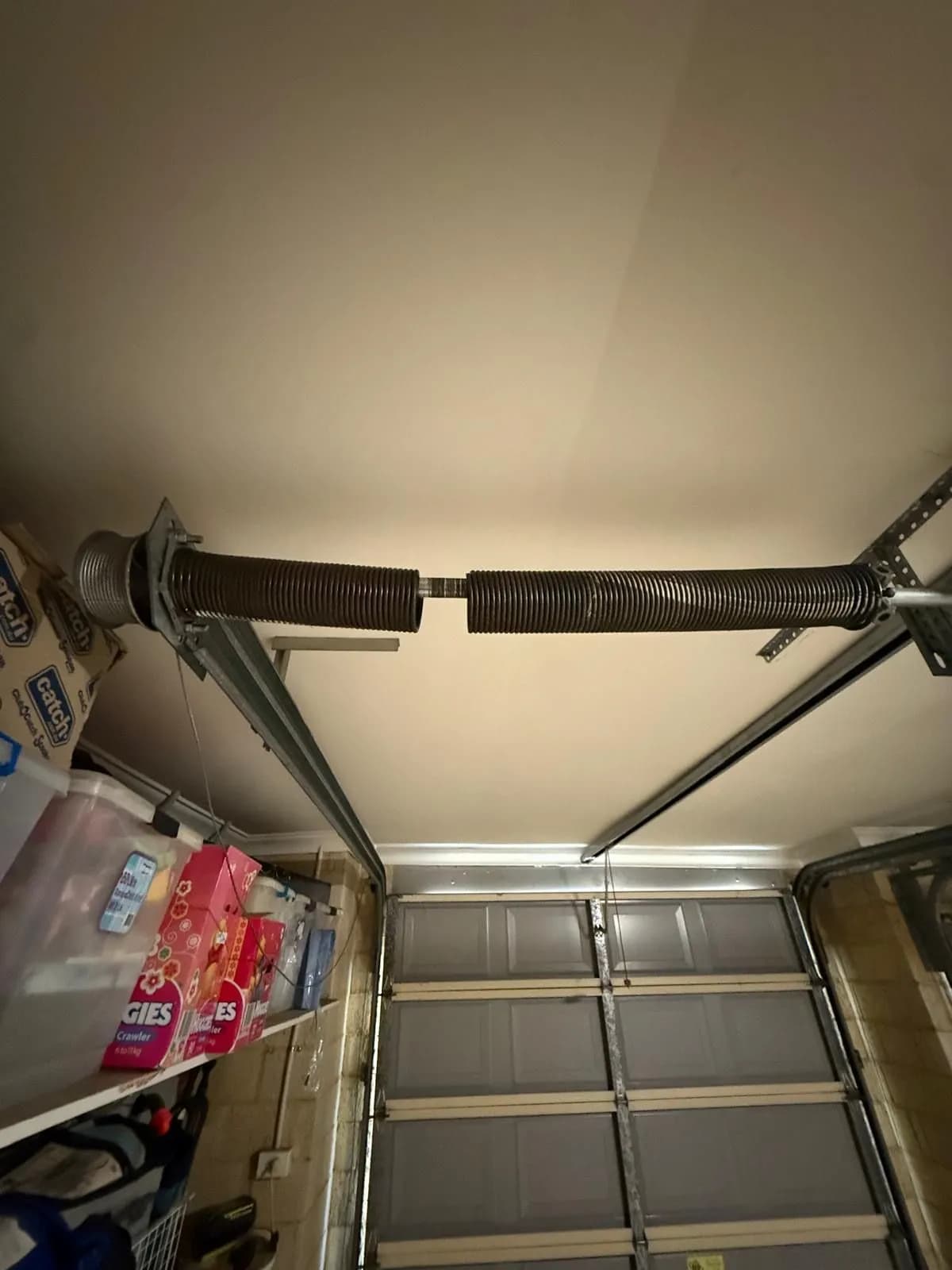 Torsion spring snapped in two with a gap between the halves above a grey sectional garage door in Mount Pleasant, Perth Torsion spring snapped in two with a gap between the halves above a grey sectional garage door in Mount Pleasant, Perth