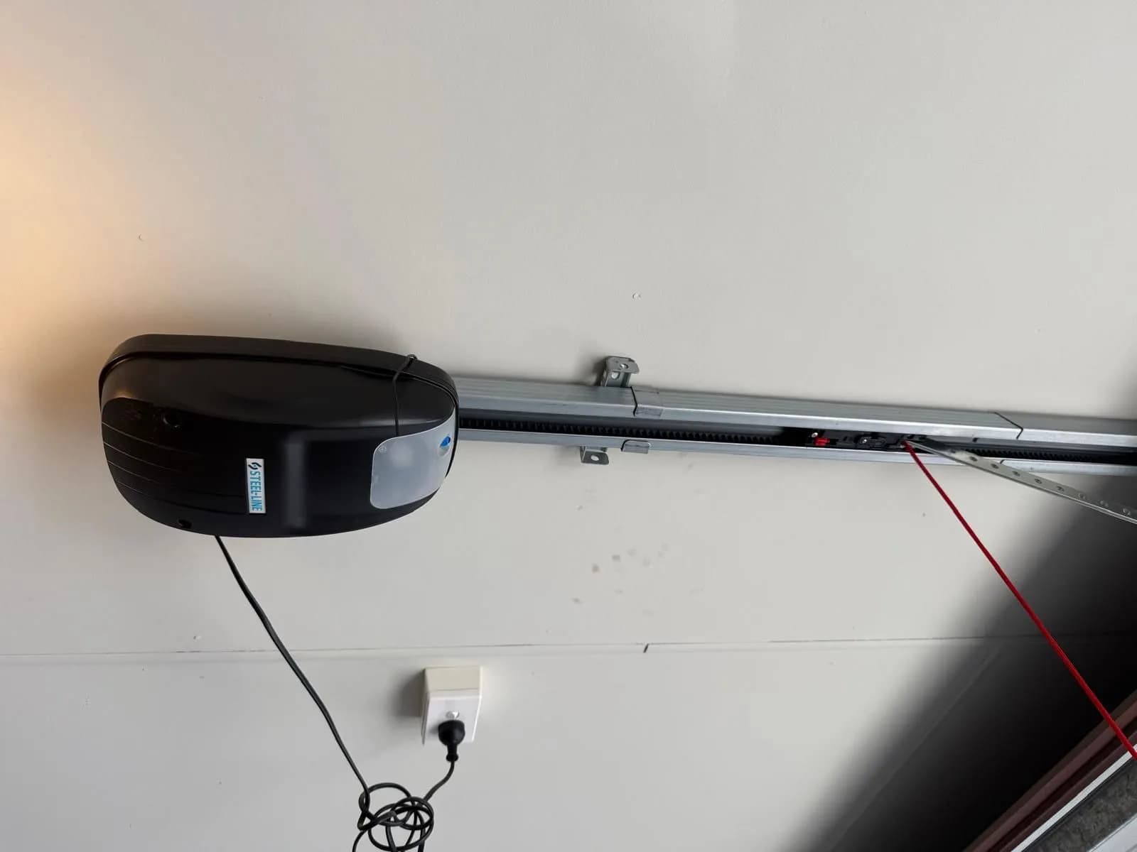 Old black Steel-Line garage door opener on the ceiling rail above a sectional door in Lynwood, Perth before replacement Old black Steel-Line garage door opener on the ceiling rail above a sectional door in Lynwood, Perth before replacement